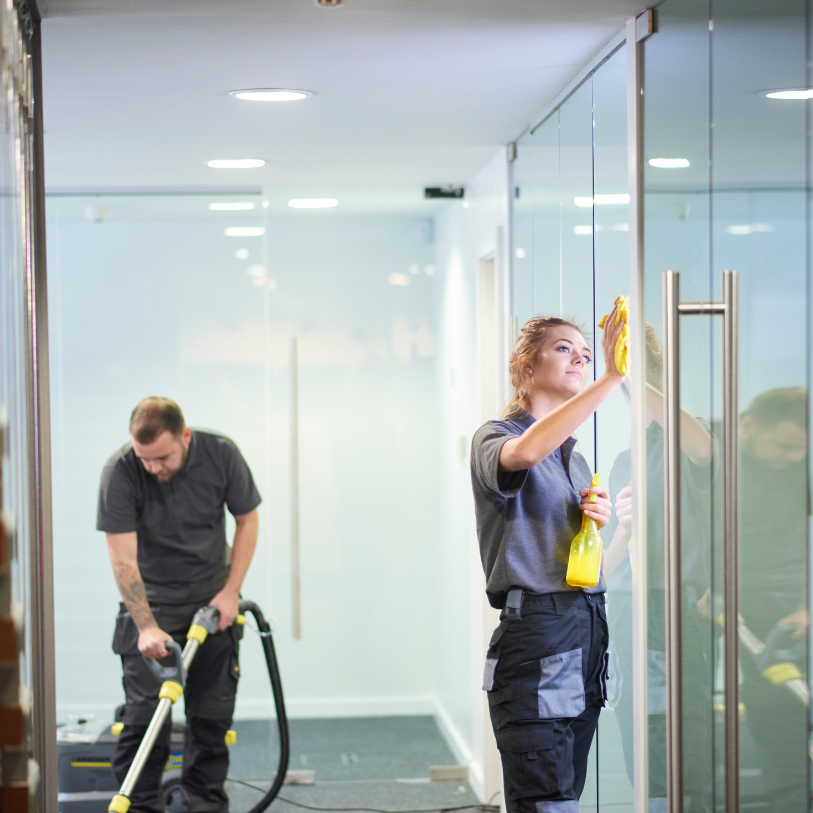 Mitarbeiterin von BP Gebäudeservice bei der Glasreinigung einer Glastrennwand im Büro
